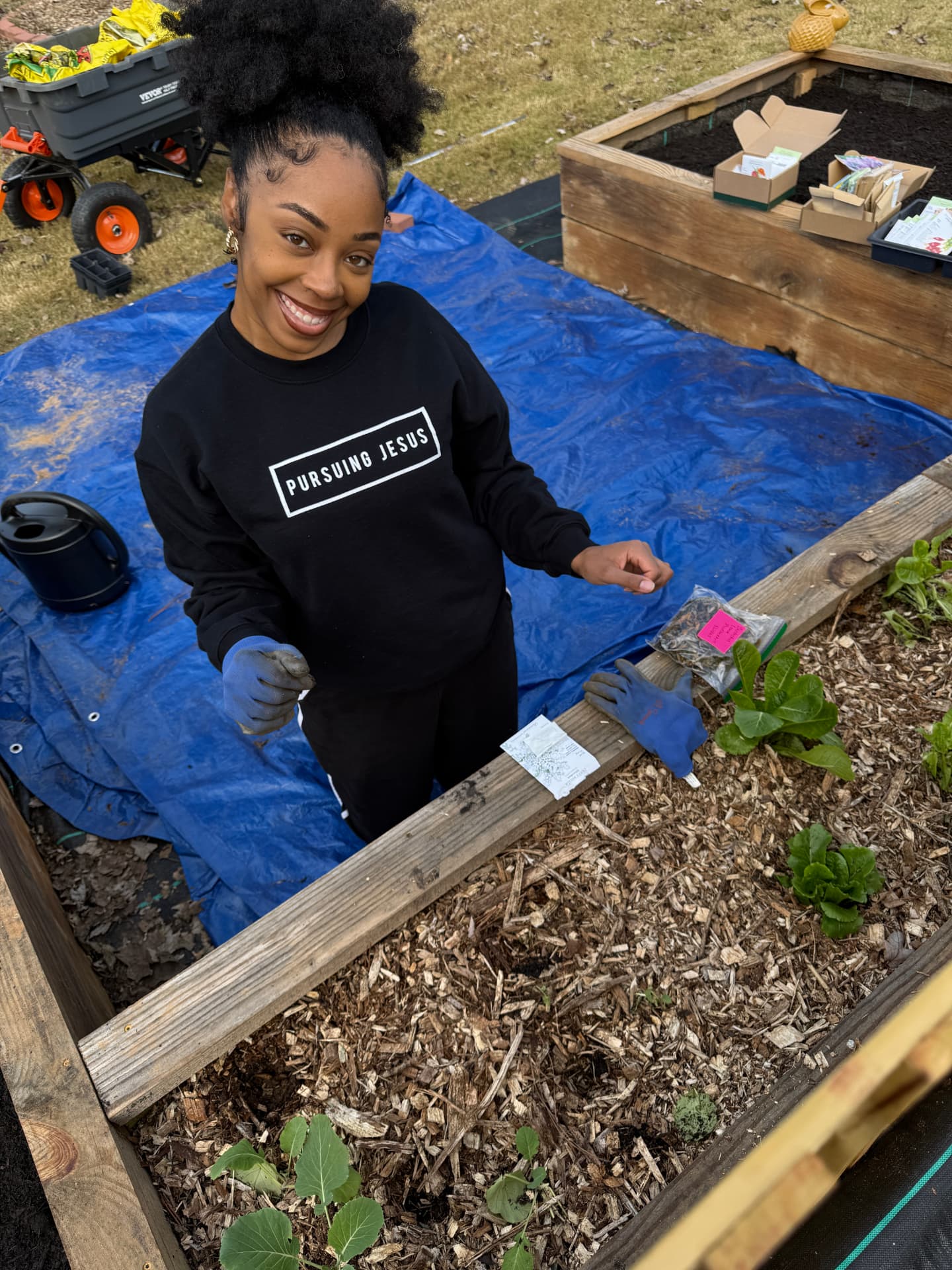 Smiling gardener planting seeds in a mulched raised garden bed